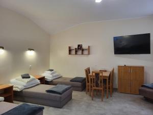 ein Wohnzimmer mit 2 Betten, einem Tisch und einem TV in der Unterkunft Hotelik OSiR Lubawa in Lubawa