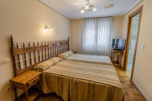 Un dormitorio con dos camas y un televisor. en Hostal Santo Domingo de Silos, en Santo Domingo de Silos