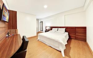 1 dormitorio con cama blanca y pared de madera en Porto Minas Hotel e Convenções, en Uberlândia