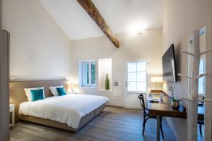 Un dormitorio con una cama y un escritorio con una computadora. en Auberge des Grands Bois, en Buchillon