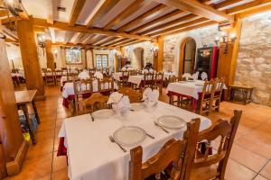 Un comedor con mesas blancas y sillas de madera. en Hostal Santo Domingo de Silos, en Santo Domingo de Silos