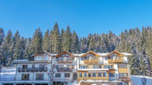 un grande edificio nella neve con gli alberi di Gartenhotel Rosenhof bei Kitzbühel a Oberndorf in Tirol