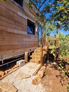 a house with wooden walls and stairs next to a tree at Location Tiny House Loule in Loulé