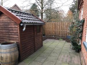 a wooden shed with a barrel next to a fence at Möblierte Wohnung mit ruhiger Terrasse in bester Lage für Feriengäste und beruflich Reisende in Ottersberg