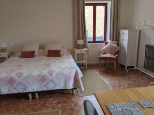 a bedroom with a bed and a chair and a window at Domaine de Fleurie in Tursac