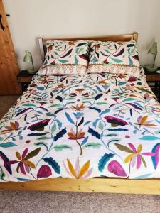 a bed with a floral comforter on it at Gorgeous 2 bedroom Kintbury cottage in Kintbury