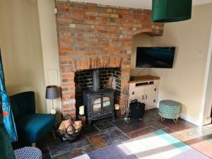 ein Wohnzimmer mit einem gemauerten Kamin und einem TV in der Unterkunft Gorgeous 2 bedroom Kintbury cottage in Kintbury