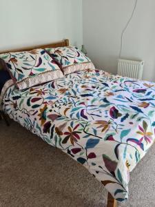 a bed with a flowered comforter in a bedroom at Gorgeous 2 bedroom Kintbury cottage in Kintbury