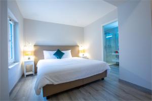 una camera da letto con un grande letto con lenzuola bianche e cuscini blu di Auberge des Grands Bois a Buchillon