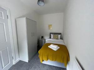 a small bedroom with a bed with a yellow blanket at Cardonald House in Glasgow