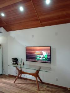 a flat screen tv on a wall with a glass table at Brandt Huss in Santa Teresa