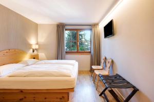 a bedroom with a bed and a chair and a window at Chalet Sonne Apt Grande in Livigno