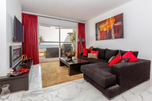 soggiorno con divano marrone e cuscini rossi di Rancho Penthouse a Mijas Costa
