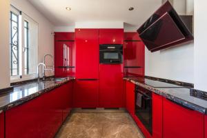 una cucina rossa con elettrodomestici neri e armadietti rossi di Rancho Penthouse a Mijas Costa