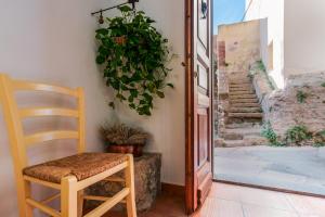 una sedia in legno seduta accanto a una porta con una pianta di La Scala del Sale a Iglesias