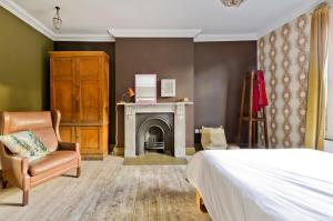1 dormitorio con 1 cama, 1 silla y chimenea en Veeve - The Artist's House en Londres
