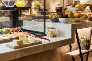 a buffet with cheese and other food on a counter at Hotel Indigo Antwerp City Centre, an IHG Hotel in Antwerp