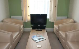 a waiting room with a couch and a television at The Swiss Cottage, Shanklin in Shanklin