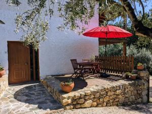 eine Terrasse mit einem Tisch und einem roten Regenschirm in der Unterkunft Casa Canela apartment and pool. in Serpins