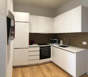 uma cozinha com armários brancos e um lavatório em The Place to Be in Sion em Sião