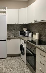 a kitchen with white cabinets and a washer and dryer at Plaza Ayuntamiento Apartment in Valencia