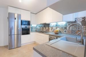 a kitchen with white cabinets and a stainless steel refrigerator at Casa Blanca in Estepona