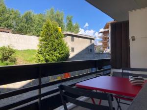 een rode tafel en een bank op een balkon bij Plein coeur de Nendaz in Nendaz