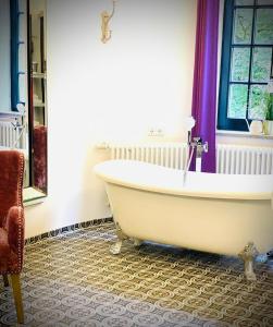 La salle de bains est pourvue d'une baignoire blanche et d'une fenêtre. dans l'établissement Sleephotels Suite Garde, à Hambourg