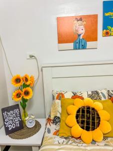 - une chambre avec un lit et un vase de tournesols dans l'établissement Bulacan Staycation At Urban Deca Homes Marilao, à Marilao