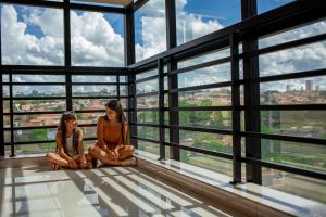 dos chicas sentadas en el piso de un edificio en ibis Styles Ribeirao Preto Maurilio Biagi en Ribeirão Preto