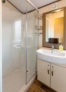 a white bathroom with a sink and a shower at Koie Holiday Home in Stranda