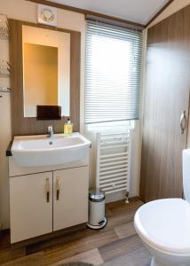 a bathroom with a sink and a toilet and a mirror at Koie Holiday Home in Stranda