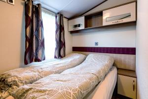 Duas camas num pequeno quarto com uma janela em Koie Holiday Home em Stranda
