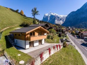 een klein huis op een heuvel naast een weg bij Chalet Eigerlicht - GRIWA RENT AG in Grindelwald
