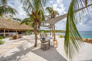 Blue Bay Villa's في الخليج الأزرق: منتجع به طاولات وكراسي على الشاطئ