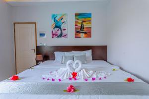 ein weißes Bett mit einem Hochzeitskleid und Blumen darauf in der Unterkunft Violet Inn Hotel in Dharavandhoo