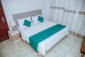 una camera da letto con un grande letto bianco con cuscini verdi di Room in BB - Martin Aviator Hotel a Kigali