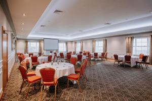 a conference room with tables and chairs and a screen at Edenmore House in Craigavon