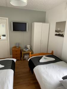 a bedroom with two beds and a flat screen tv at Alderley Hotel Blackpool in Blackpool
