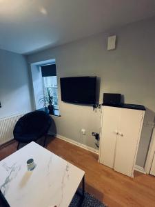 a living room with a table and a tv on the wall at Cosy studio flat in Montrose