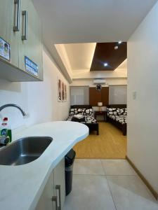 een keuken met een wastafel en een woonkamer bij CedarPeak213b in Baguio