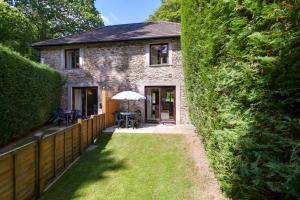 ein Steinhaus mit einem Zaun und einem Hof in der Unterkunft Crylla Valley Cottages - access to pool, gym, spa and more in Saltash
