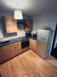 a kitchen with a stainless steel refrigerator and wooden cabinets at Cosy studio flat in Montrose