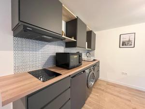 a kitchen with a counter with a microwave and a washing machine at Le Morétain - 400m gare - Jardin - centre ville in Moret-sur-Loing