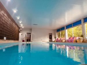 a large swimming pool with blue water in a building at Les Moulins Du Duc ÉCOLODGE in Moëlan-sur-Mer