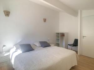 a white bedroom with a bed with two blue pillows at La Parenthèse maison T3 au calme avec parking gratuit in Les-Pennes-Mirabeau