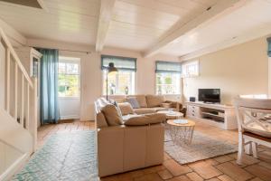 a living room with a couch and a tv at Altes Schulmeisterhaus Wohnung 2 in Oevenum