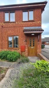 una casa de ladrillo rojo con puerta de madera en The Kingfisher, by Spires Accommodation a great place to stay for Drayton Manor Park and The NEC, en Kingsbury