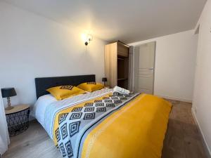 1 dormitorio con 1 cama grande con almohadas amarillas en Le Morétain - 400m gare - Jardin - centre ville, en Moret-sur-Loing