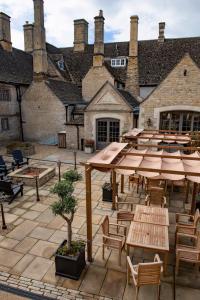 a patio with tables and chairs and a building at The Haycock Manor Hotel in Wansford